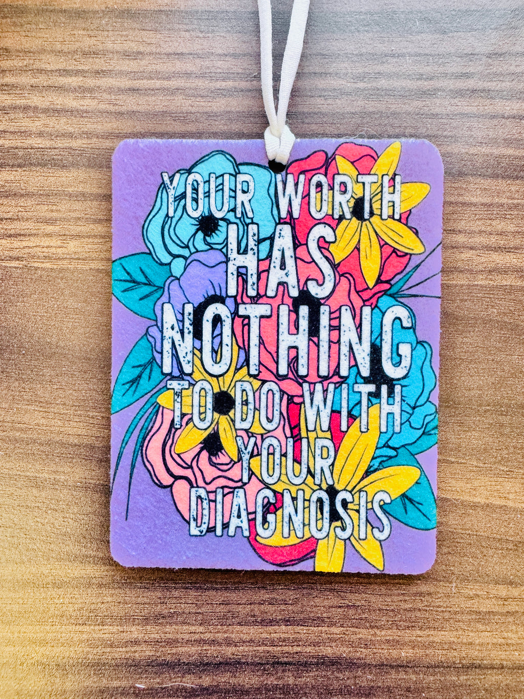 Colorful card with floral design and motivational quote on a wooden surface