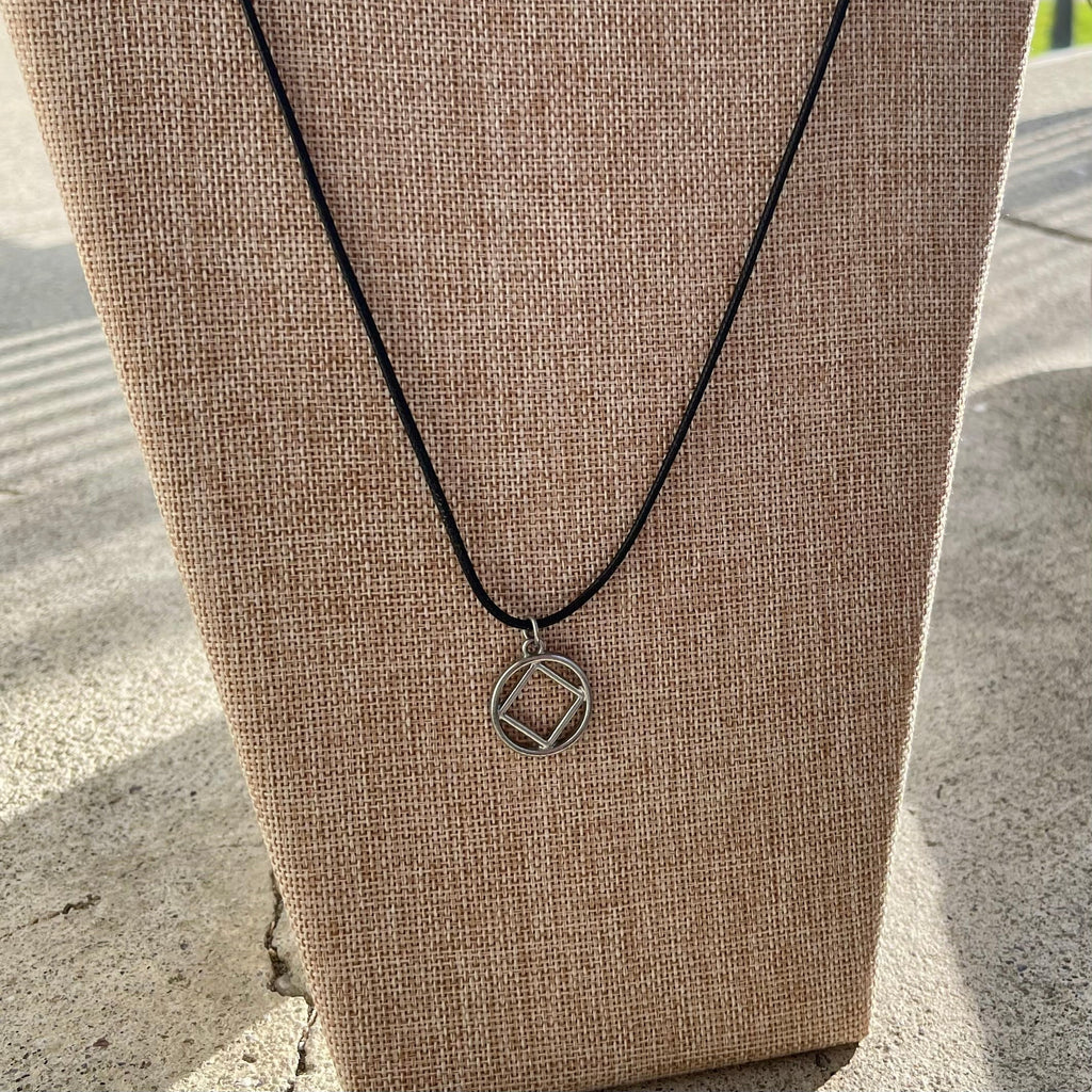 Necklace with a narcotics anonymous pendant on a brown surface