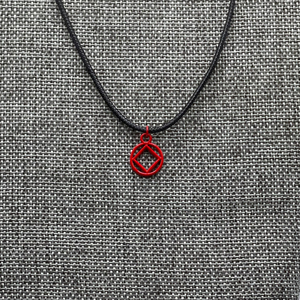 A red coated stainless steel Narcotics Anonymous symbol necklace displayed on a grey textured mannequin.